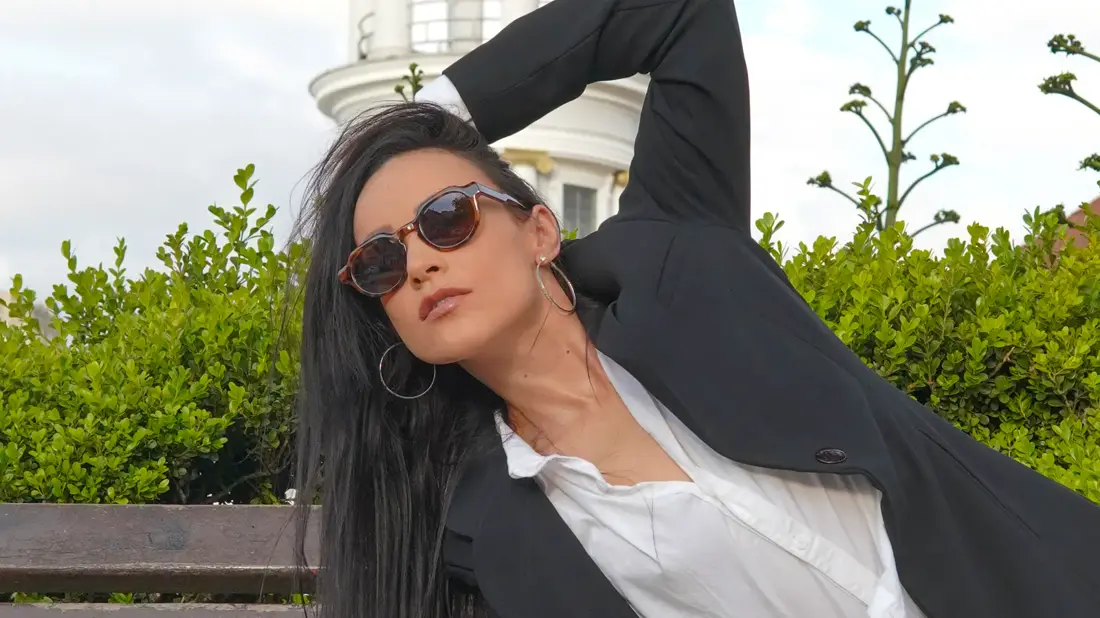 Carol Telles deitada em um banco, de óculos escuros
